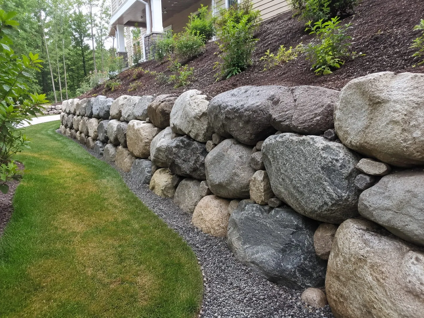 Boulder retaining wall contractors placing rock in Auckland